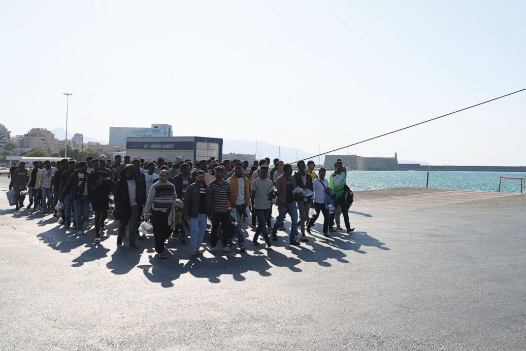 Μετανάστες περπατάνε σε προκυμαία